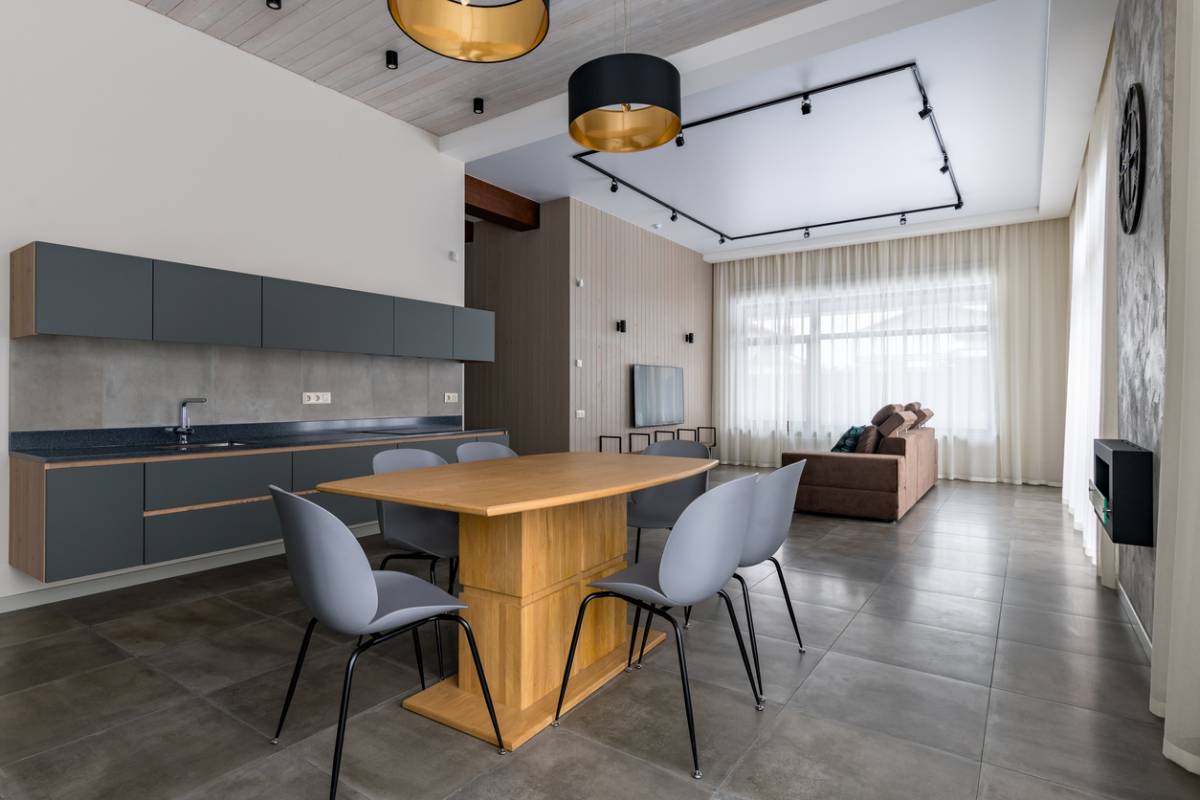 Vaste pièce de vie avec cuisine ouverte et un carrelage durable en grès cérame gris, alliant esthétisme et facilité d'entretien.